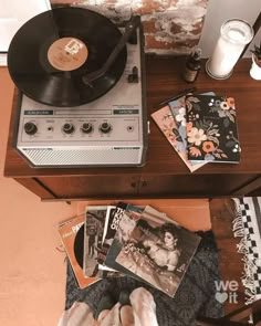 a record player sitting on top of a wooden table next to a pile of records