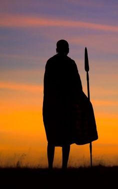 the silhouette of a man holding a spear in front of an orange and blue sky