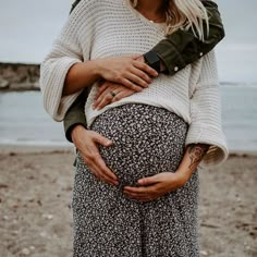 a pregnant woman holding her stomach on the beach