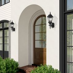 a white house with black shutters and two lights on the front door is shown