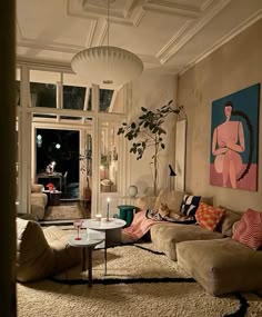 a living room filled with lots of furniture next to a large painting on the wall