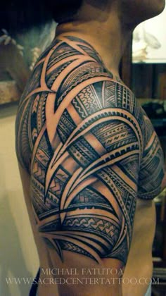 the back of a man's shoulder with an intricate tattoo design on his arm