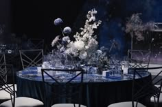 the table is set with white flowers and blue linens for an elegant dinner party