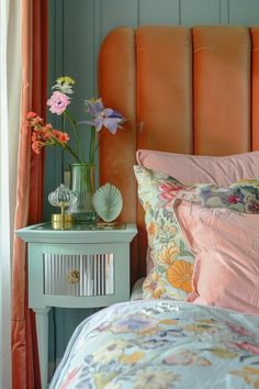 an orange headboard with flowers in a vase on the end table next to it