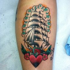 a tattoo on the leg of a person with a heart and ship in it's center