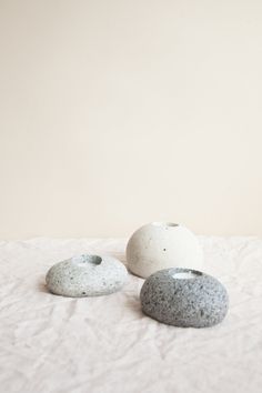 three white and gray rocks sitting on top of a bed