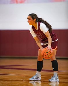 a woman holding a basketball on top of a court