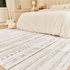 a large white bed sitting on top of a hard wood floor next to a window