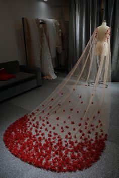 a wedding dress with red rose petals on the floor