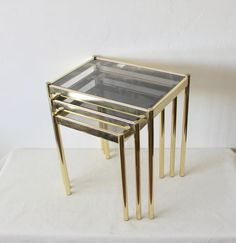 three glass and brass nesting tables on a white surface