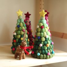 two felt christmas trees on top of a wooden shelf