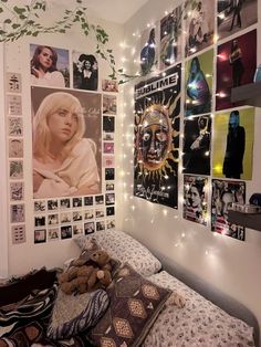 a bedroom with posters on the wall and a teddy bear laying on the bed in front of it