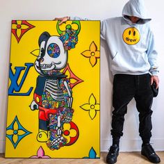 a man standing next to a large painting with a skull on it's face