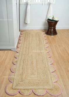 a rug with pink scalloped edges on the floor in front of a door