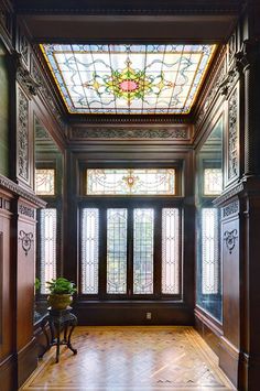 an empty room with stained glass windows and wooden flooring on the walls, along with a bench