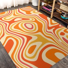 an orange and yellow area rug on the floor in front of a bookshelf