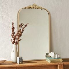 a mirror and vase on a wooden table