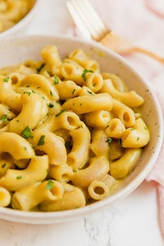 a white bowl filled with macaroni and cheese on top of a marble table