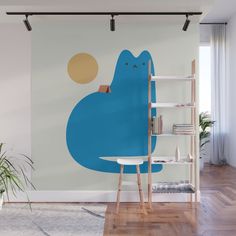 a blue cat sitting on top of a table next to a book shelf in front of a window