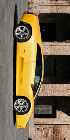 a yellow sports car parked in front of a building