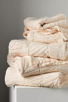 a stack of folded towels sitting on top of a white table next to a wall