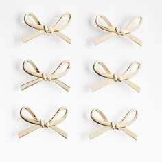 four pairs of gold bow clips on white background