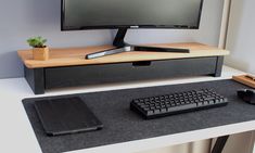 a computer desk with a keyboard, mouse and monitor on it's stand next to a plant