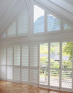 an empty room with wooden floors and white shutters