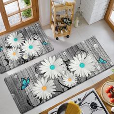 two kitchen mats with daisies and butterflies on them in the middle of a room