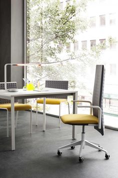 a white table with yellow chairs in front of a large window and a glass wall