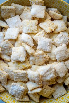 a yellow and white bowl filled with sugar cubes on top of a blue table