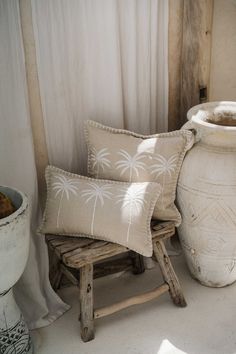 two white vases sitting next to each other on top of a wooden bench in front of a window