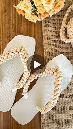 a pair of white sandals sitting on top of a wooden floor next to a bouquet of flowers