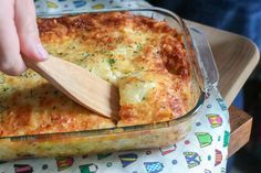 a wooden spoon in a casserole dish with cheese