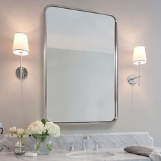 a bathroom sink with a large mirror above it and two lights on the wall behind it