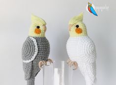 two crocheted parrots sitting on top of each other in front of a glass vase