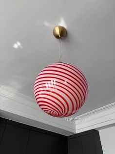 a red and white striped light hanging from the ceiling in a room with black cabinets