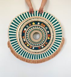 a person standing next to a round rug with tassels on the bottom and sides