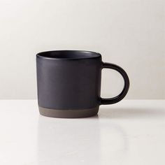 a black coffee cup sitting on top of a white counter