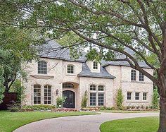 a large brick house sitting on top of a lush green field next to a tree