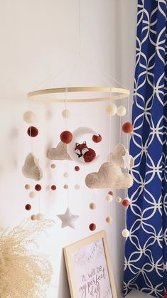 a baby crib mobile is hanging from the wall next to a framed photo and a blue curtain