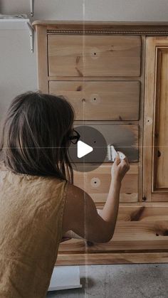 a woman is painting a wooden cabinet with white paint