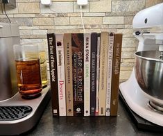 a stack of books sitting on top of a counter next to a mixer