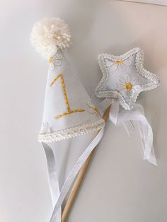 two small hats are sitting next to each other on a white tablecloth and wooden stick