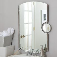 a bathroom sink sitting under a large mirror next to a trash can and tissue dispenser