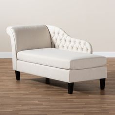 a white chaise lounge chair sitting on top of a hard wood floor next to a wall