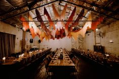 an empty dining room with long tables and hanging orange streamers in the ceiling above