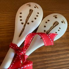 two wooden spoons with designs on them tied to a red and white polka dot ribbon