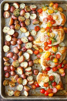 chicken, potatoes and tomatoes on a baking sheet