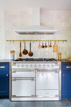 a stove top oven sitting inside of a kitchen next to blue cupboards and counter tops